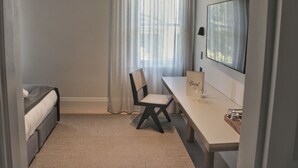 A bedroom with a bed, a desk, a chair, a window with curtains, and a mirror on the wall. - The Bowral Hotel (Bowral)
