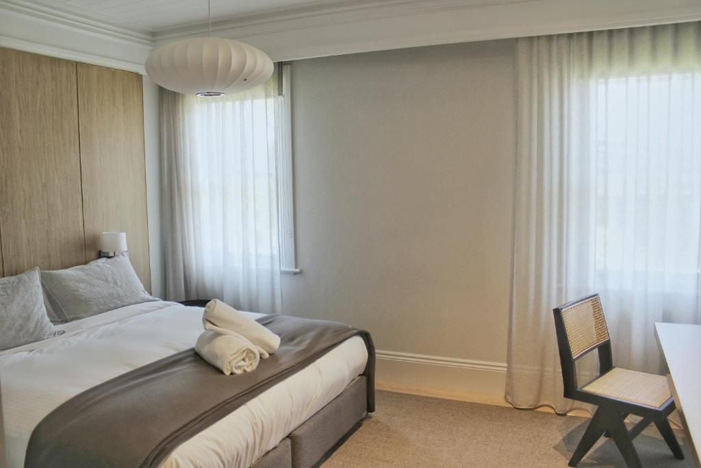 A hotel room with a bed, a chair, a table, and a window with curtains.