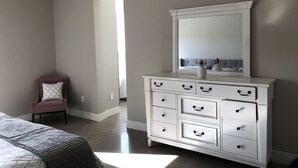 A bedroom with a white dresser, a mirror, and a chair. - MONTHLY RENTAL ONLY  (Hurricane)