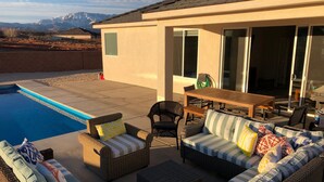 A poolside area with wicker furniture, a dining table, and a view of mountains. - MONTHLY RENTAL ONLY  (Hurricane)