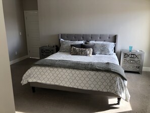 Une chambre à coucher avec un lit, des tables de chevet, une commode et une porte.
