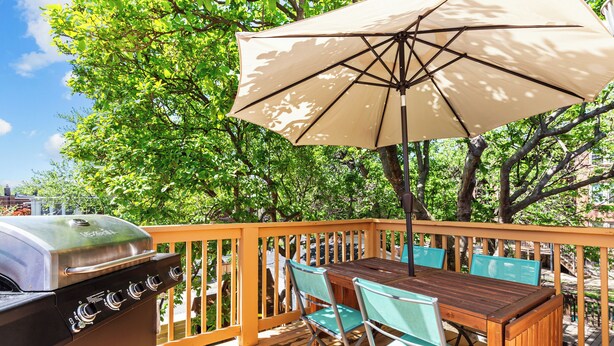 An outdoor deck with a grill, wooden table, chairs, and an umbrella. - Family Friendly , Fully Renovated 3BR Luxury Home. Centrally located in St.Louis (St. Louis)