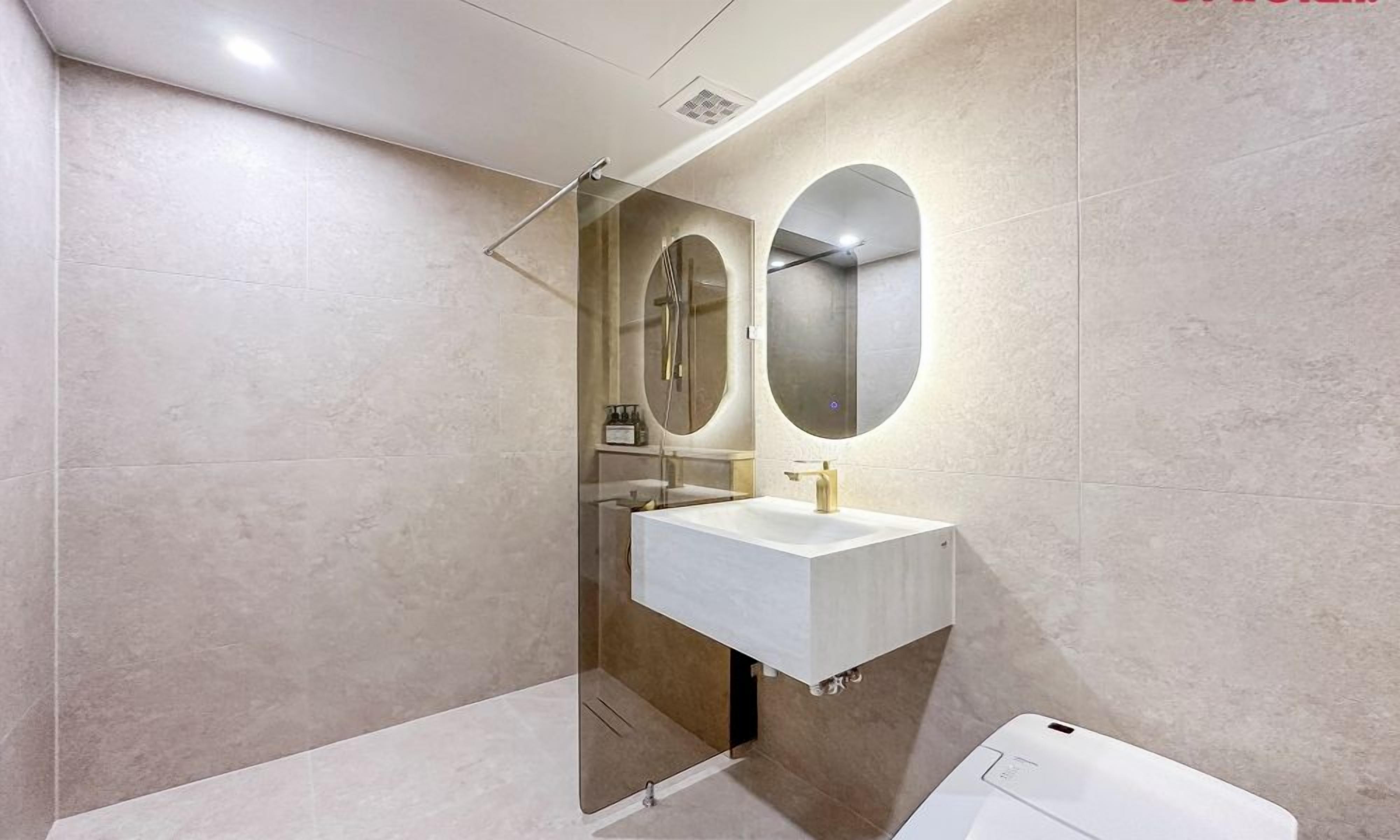 Une salle de bain moderne avec une douche à parois de verre, un lavabo blanc et deux miroirs fixés au mur.
