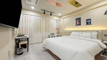 Una habitación de hotel con una cama grande, un televisor, un escritorio y un cubo de basura.