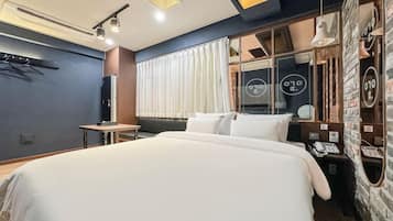 Een moderne hotelkamer met een groot bed, een bureau, een telefoon en een raam met gordijnen.