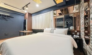 Habitación de hotel moderna con una cama grande, un escritorio, un teléfono y un ventanal con cortinas.
