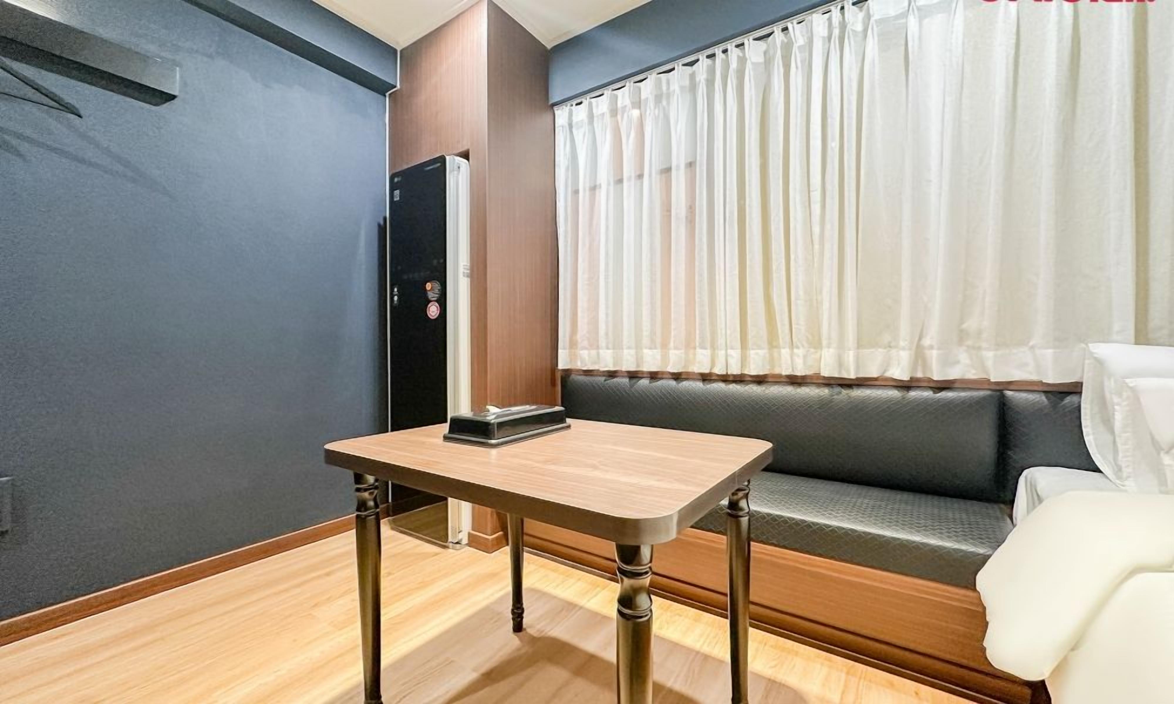 Una habitación con una mesa, un sofá, una puerta y una ventana con cortinas.