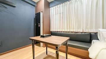 Una habitación con una mesa, un sofá, una puerta y una ventana con cortinas.