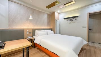 A hotel room with a bed, bedside table, and a desk.