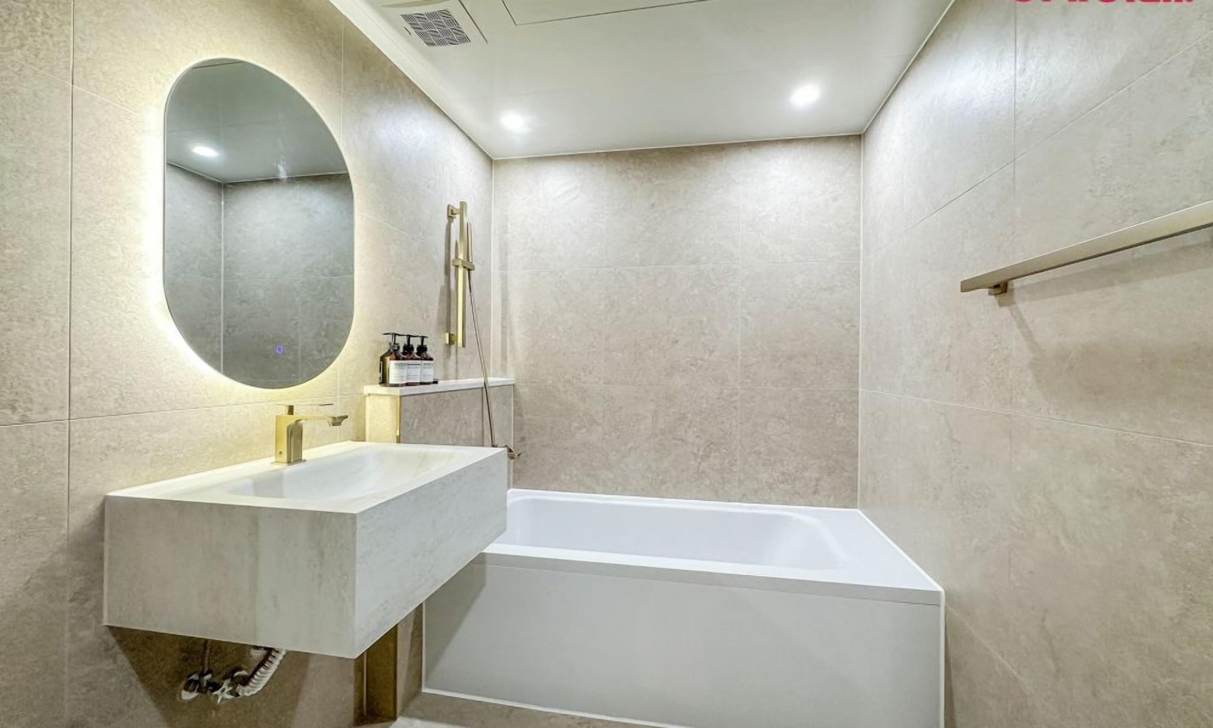 A modern bathroom with a rectangular bathtub, a sink with a mirror, and a shower area.