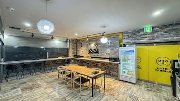 A modern hotel lobby with a bar area, seating arrangements, and a refrigerator stocked with beverages.