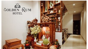 A reception area with a wooden display featuring traditional Chinese decorations, a sign for the Golden Rum Hotel, and a marble floor. - Golden Rum Hotel (Xuan Huong - Da Lat)