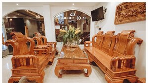 A hotel lobby with wooden furniture, a central coffee table, and a large window with the hotel name. - Golden Rum Hotel (Xuan Huong - Da Lat)