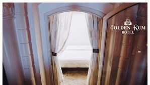 A doorway leading to a bed with white curtains, a wooden floor, and a sign for the Golden Rum Hotel. - Golden Rum Hotel (Xuan Huong - Da Lat)