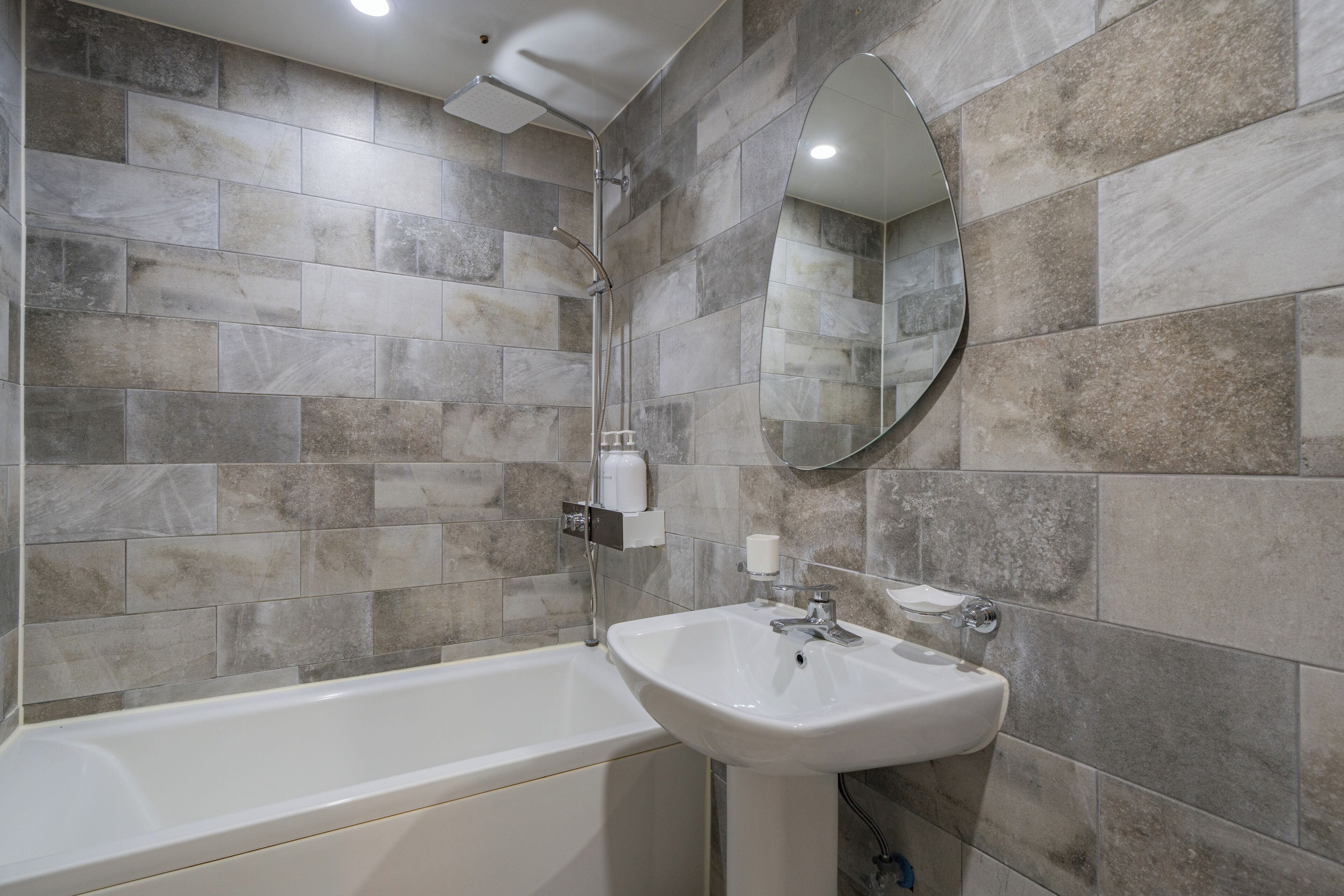 Un baño moderno con bañera, lavamanos y espejo.