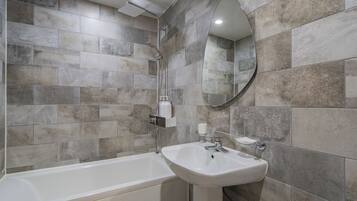 Un baño moderno con bañera, lavamanos y espejo.