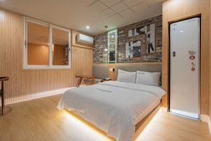 A hotel room with a bed, wooden floor, a brick wall, and a white door. - HOTEL Yeogiuhtte Gwangju Station (Gwangju)