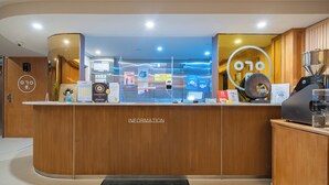Una recepción con mostrador de madera, una pantalla digital y una máquina de café.