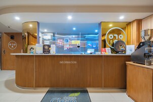 Una recepción con mostrador de madera, una pantalla digital y una máquina de café.