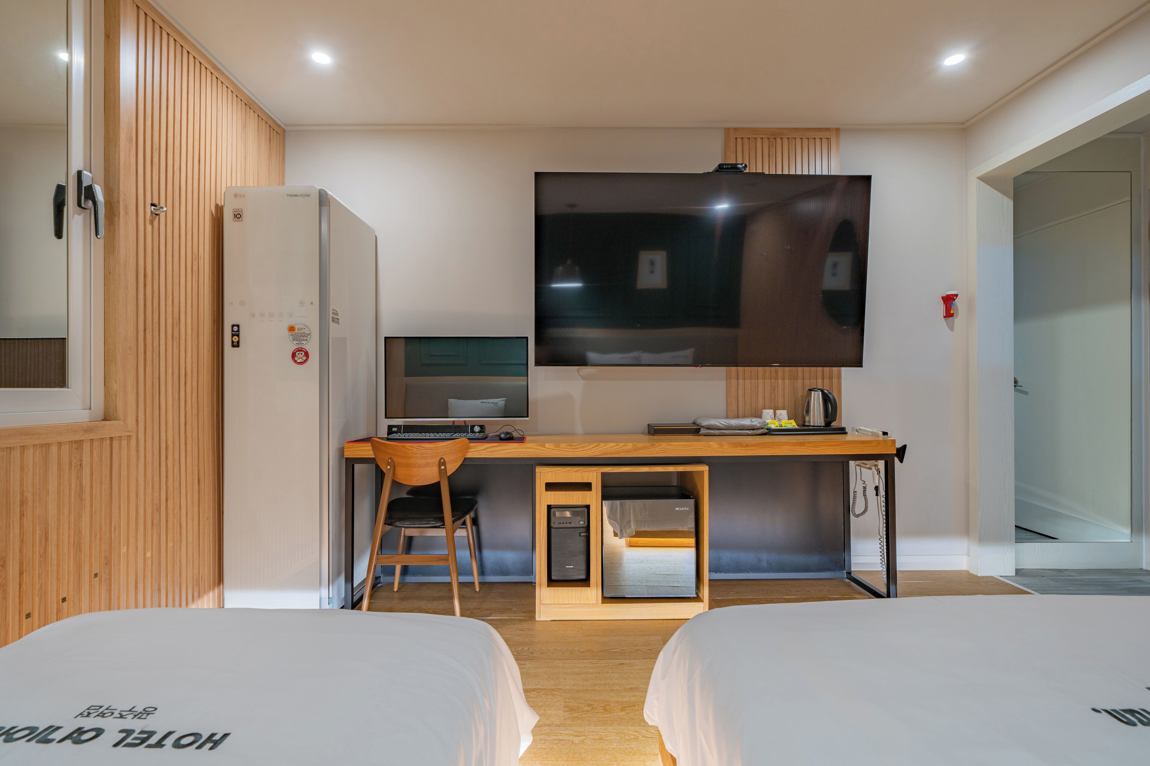 Habitación de hotel con dos camas, un escritorio con computadora, un televisor y un minibar.