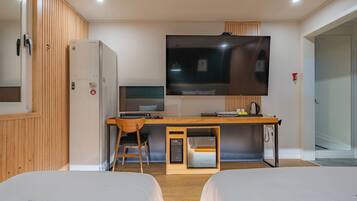 Habitación de hotel con dos camas, un escritorio con computadora, un televisor y un minibar.