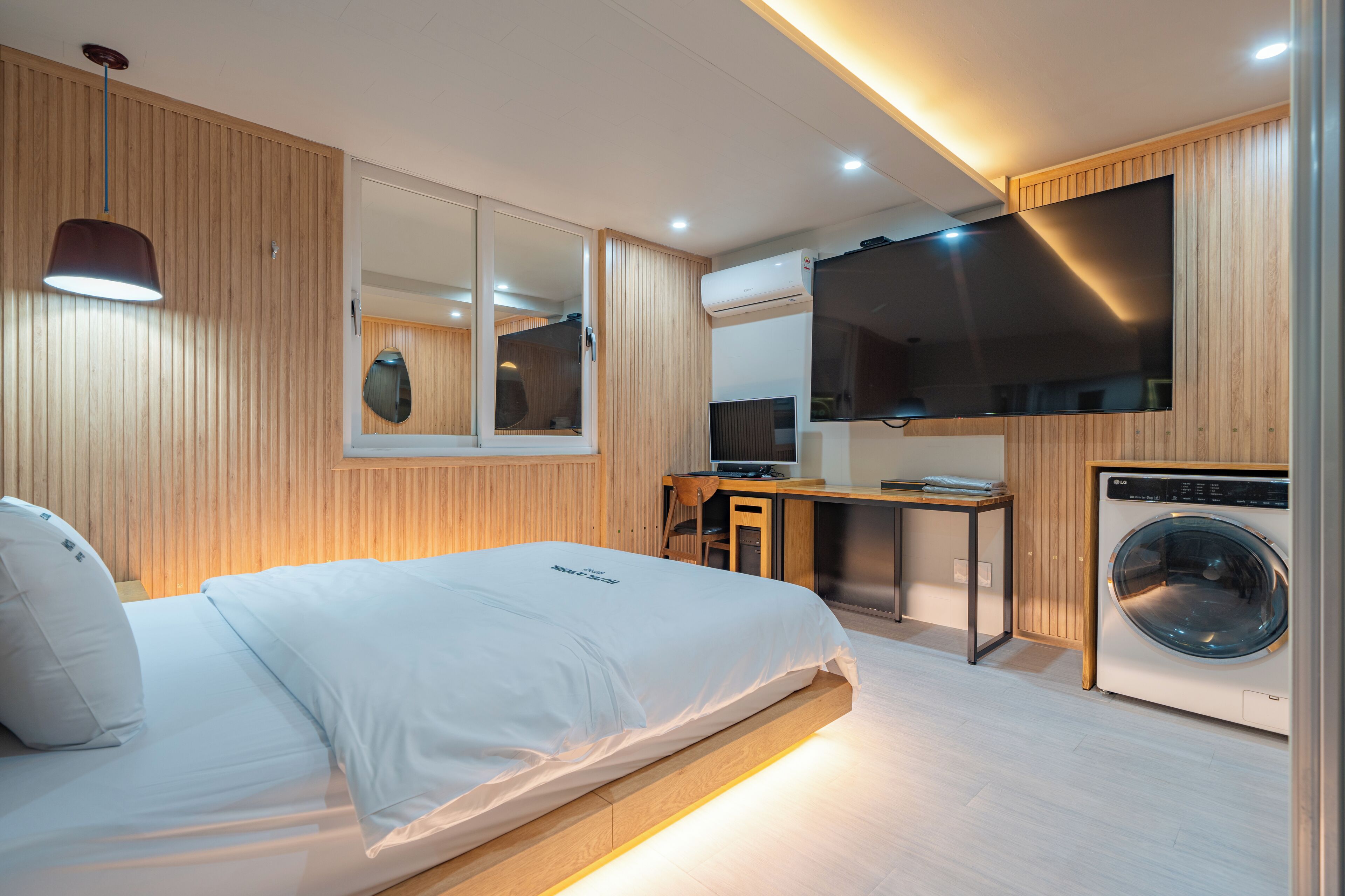 Una camera da letto moderna con un letto, una scrivania, una TV e una lavatrice.