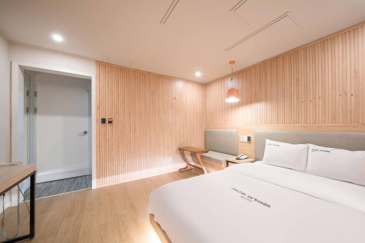 Una habitación de hotel moderna con una cama grande, un escritorio y una zona de estar.
