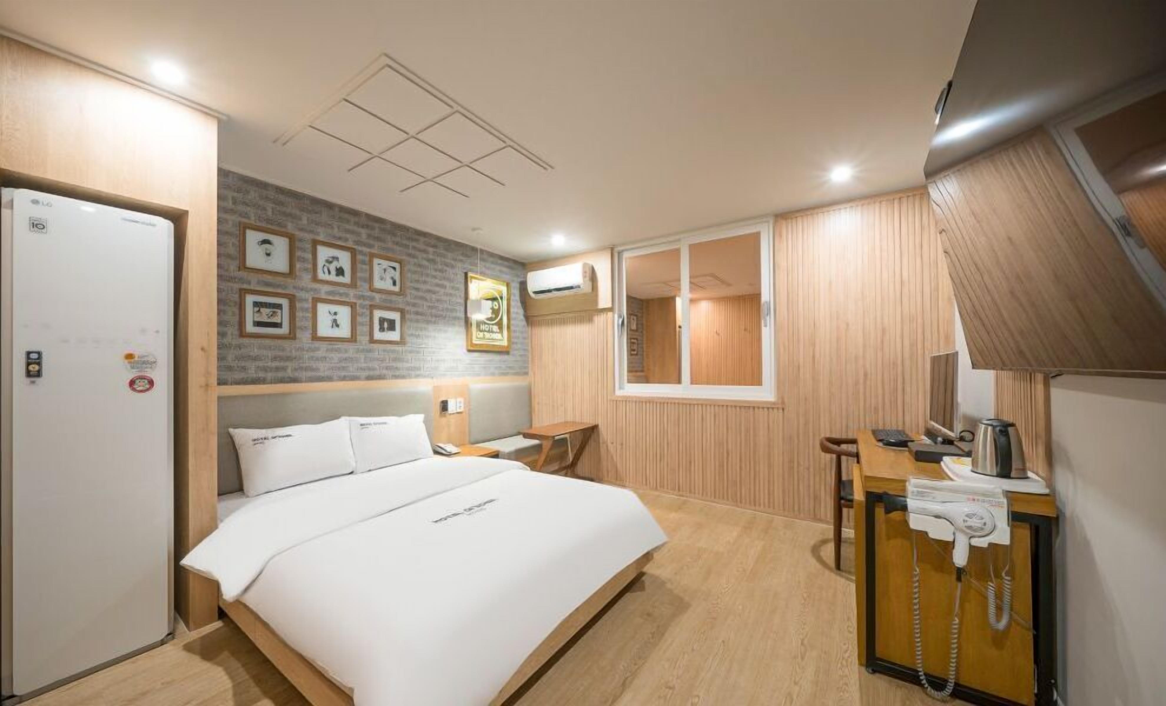 Habitación de hotel con cama, escritorio, teléfono, espejo y ventana.