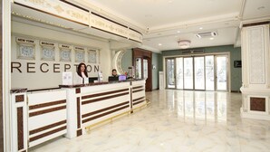 A reception area with a marble floor, a reception desk, and clocks displaying times in New York, Moscow, Istanbul, and London. -  Altus Hotel Baku - Free Massage (Baku)