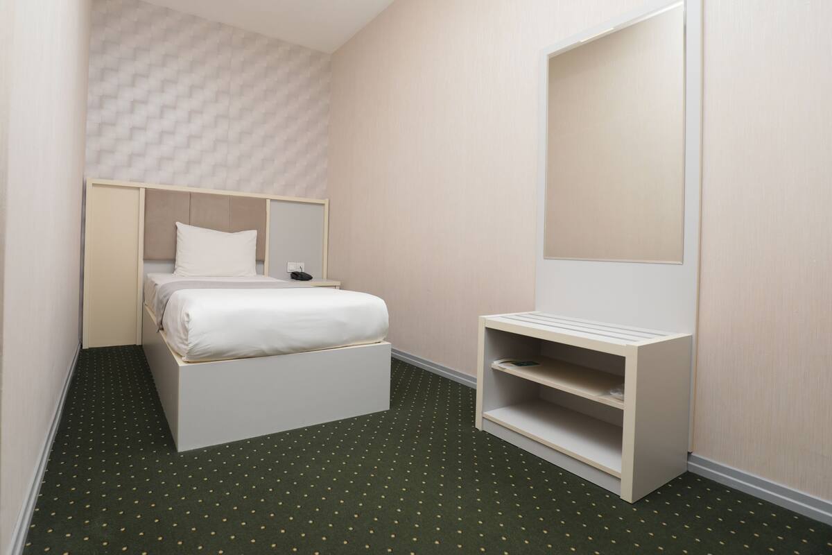 Une chambre d’hôtel comprenant un lit, une table de chevet, un miroir et une étagère intégrée.