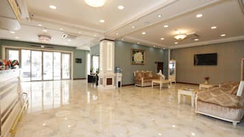 A spacious lobby with a marble floor, a fireplace, and a large sofa.