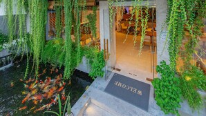 A hotel entrance with a sign reading "Ponte Villa," surrounded by lush greenery and a koi pond. - Ponte Boutique Villa (Da Nang)