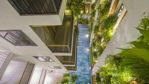 A modern indoor pool with a glass floor, surrounded by lush greenery and architectural balconies. - Ponte Boutique Villa (Da Nang)