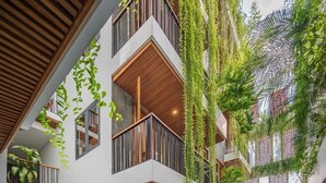 A multi-level building with balconies, a central water feature, and lush greenery. - Ponte Boutique Villa (Da Nang)