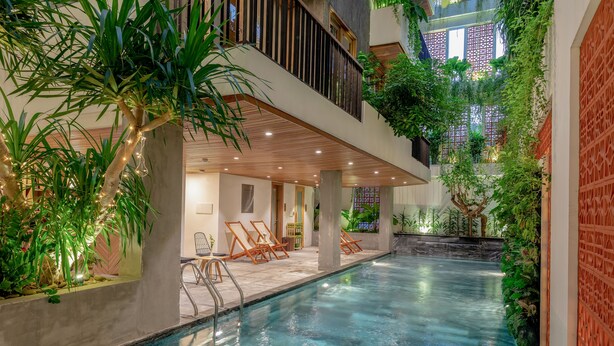An indoor swimming pool with lounge chairs, a wooden deck, and lush greenery. - Ponte Boutique Villa (Da Nang)