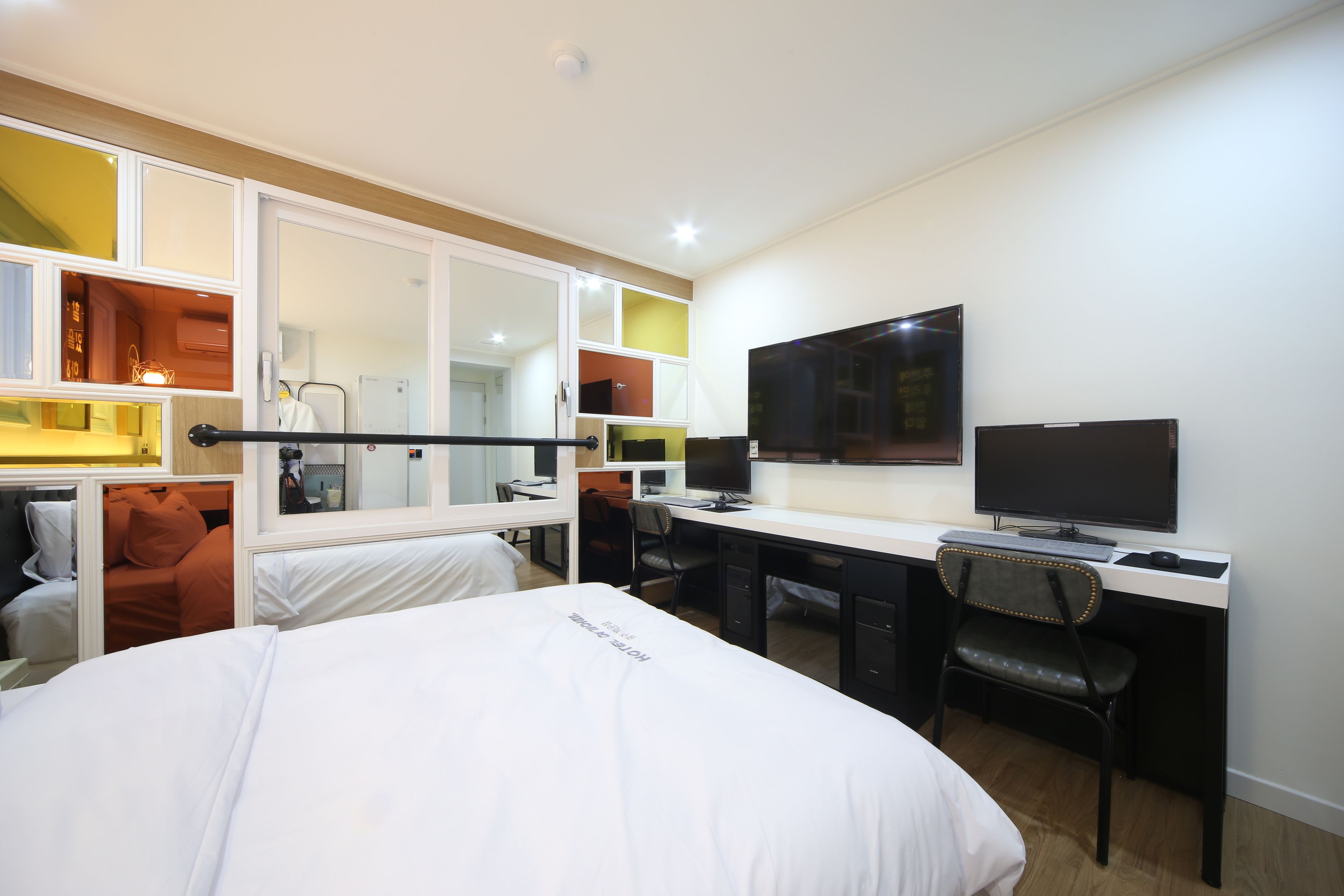 A hotel room with a bed, desk, chair, television, and wardrobe.