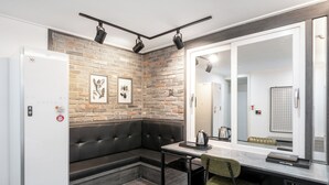 A modern hotel room with a brick wall, a black leather sofa, a dining table, and a large mirror. - HOTEL Yeogiuhtte Gwangju Baek Un (Gwangju)