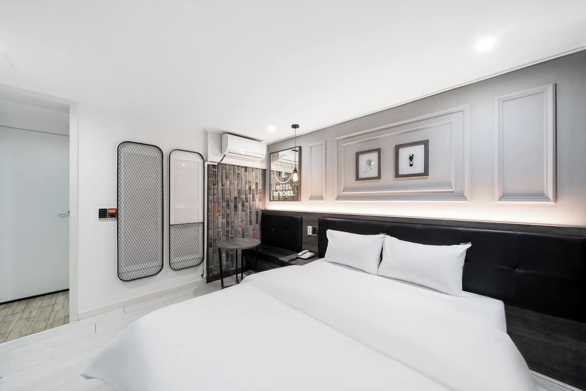 A modern hotel room with a large bed, a small table, and a mirror.