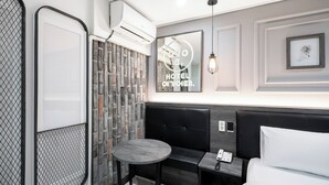 A modern hotel room with a black leather sofa, a small round table, a bed with white linens, and a wall-mounted air conditioner. - HOTEL Yeogiuhtte Gwangju Baek Un (Gwangju)