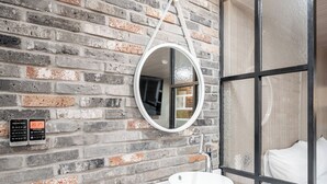 A bathroom with a white sink, a round mirror, and a brick wall. - HOTEL Yeogiuhtte Gwangju Baek Un (Gwangju)