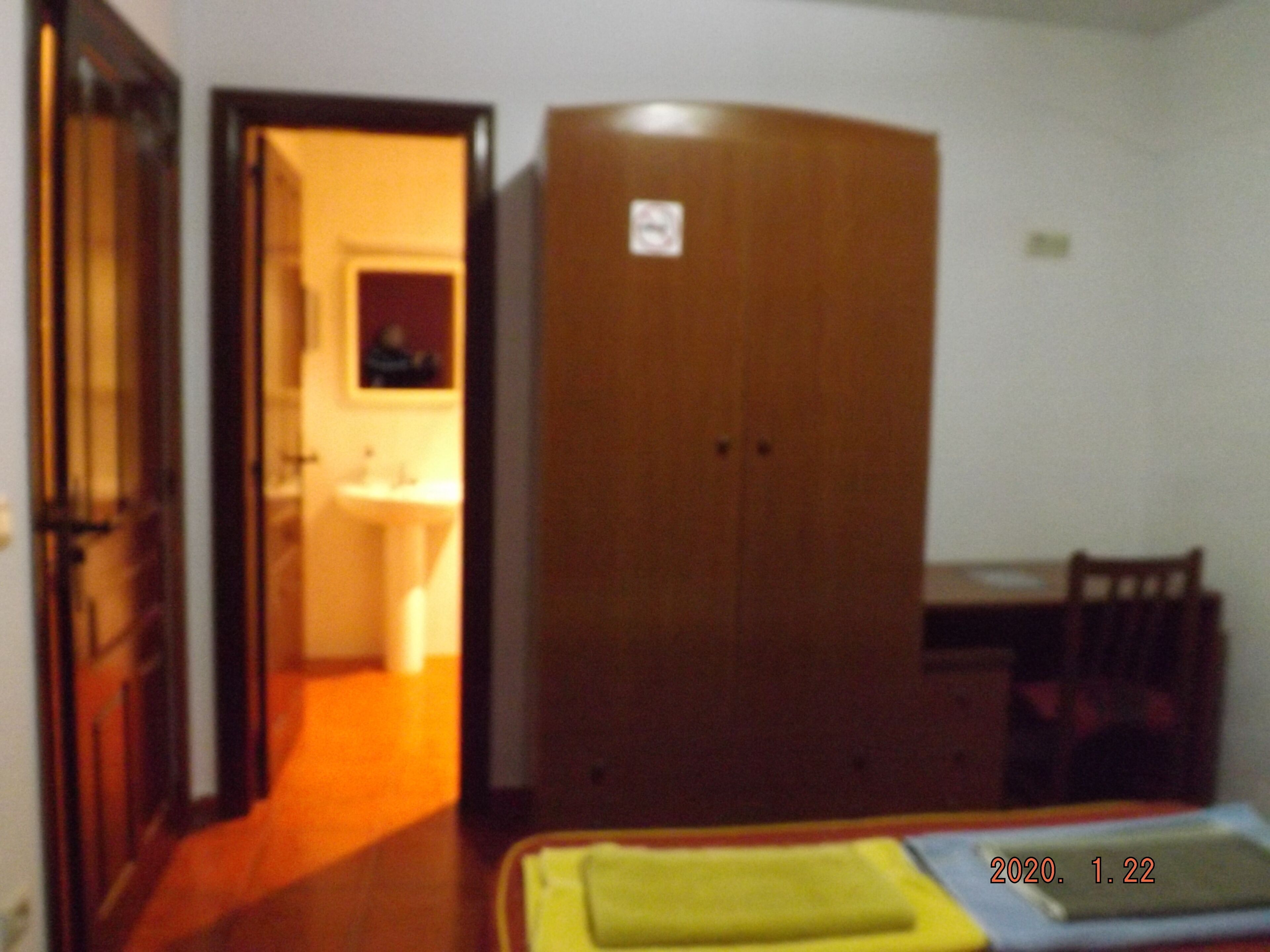 Une chambre à coucher avec un lit, une armoire en bois, un bureau et une chaise.