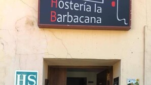 Une entrée d’immeuble avec une enseigne indiquant « Hostería la Barbacana » et un panneau sur le mur indiquant « HS ».