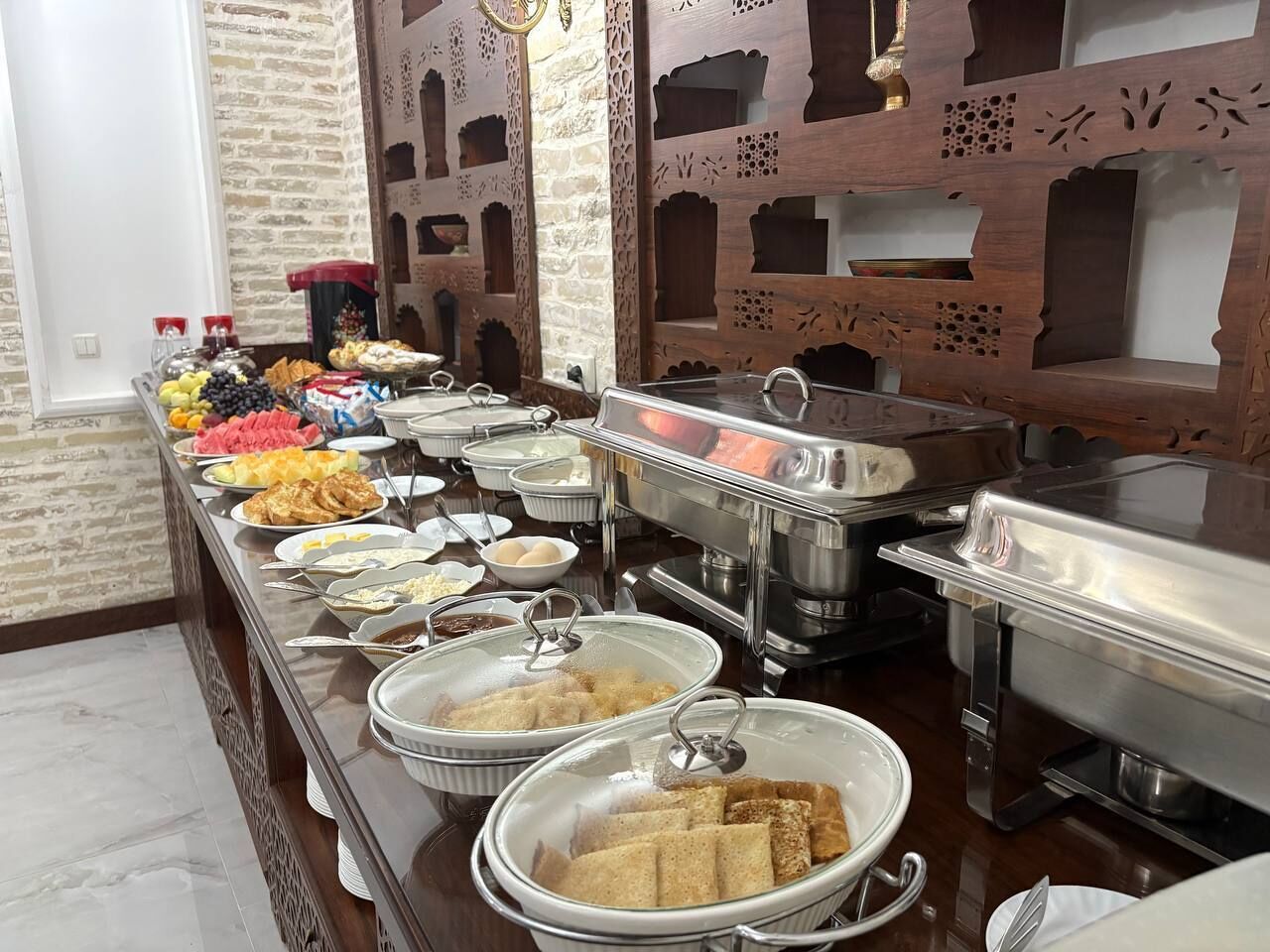 Ein reichhaltiges Buffet mit verschiedenen Speisen und einer Wand mit aufwendigen Mustern.