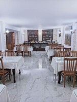 Un restaurante con suelos de mármol, mesas y sillas de madera, y una zona de bufé central con platos.