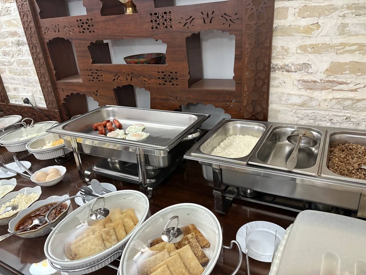 Un buffet proposant une variété de plats, notamment des œufs, des saucisses et du riz.