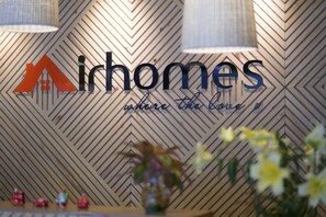 A sign with the text "Airhomes" and a logo, set against a wooden wall with a chevron pattern. - Hotel Airhomes (Ho Chi Minh City)