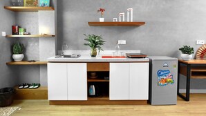 Eine moderne Küche mit weißen Schränken, einem integrierten Kühlschrank und Holzregalen.