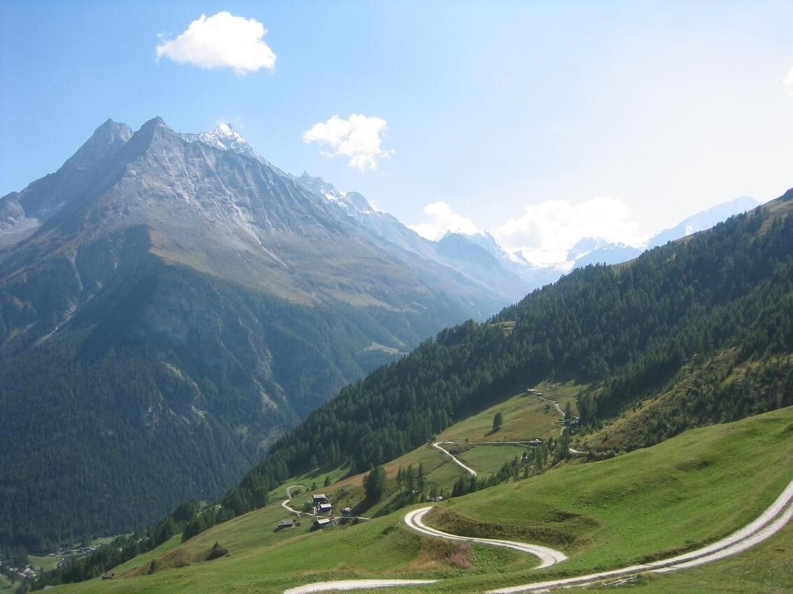 A winding road through a mountainous landscape with a prominent peak in the background.