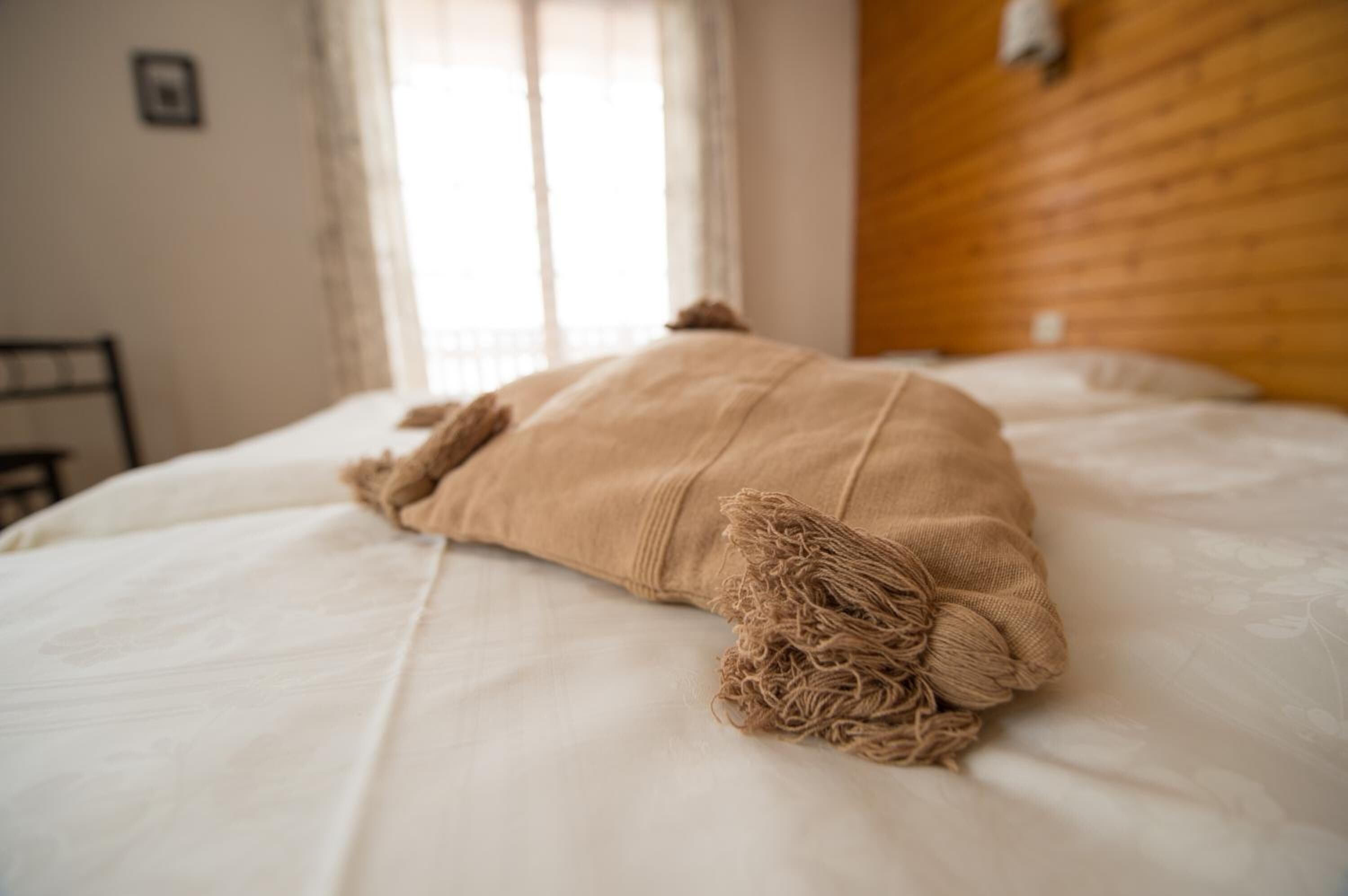 A bed with a beige blanket and a wooden headboard.