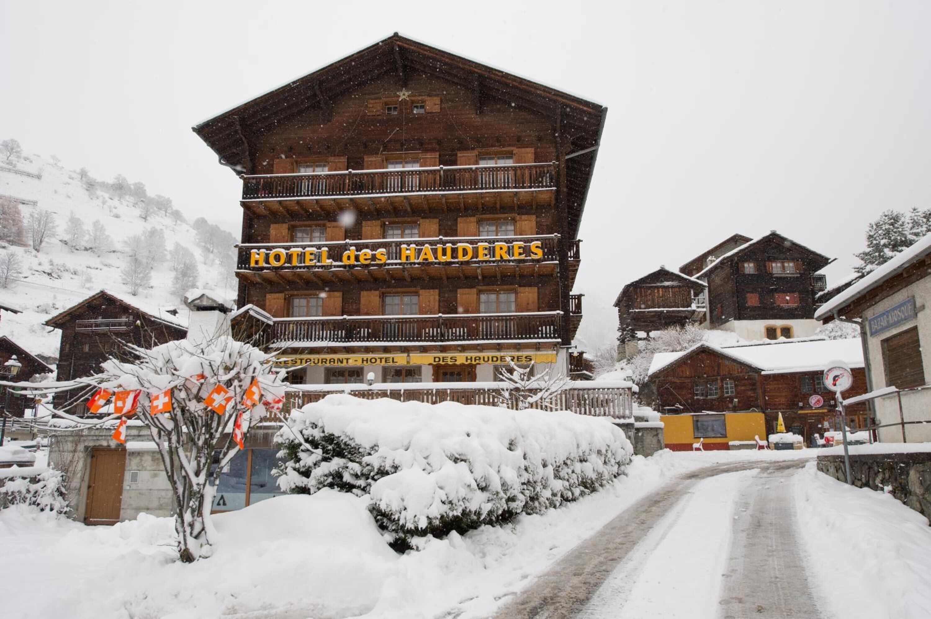 Un immeuble en bois à plusieurs étages, doté de balcons, portant l’inscription « HÔTEL des HAUDERES ».
